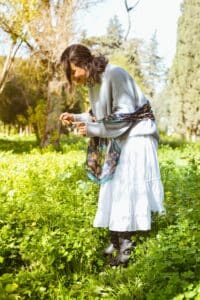 a woman in a white dress is picking flowers in the middle of a meadow
