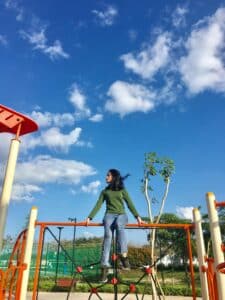 a woman sits on top of a children's jungle gym on a sunny day