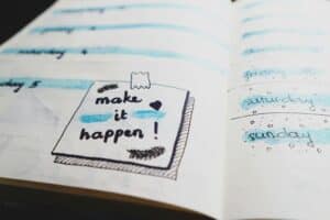a drawing of a post-it note in a planner states "Make it happen"